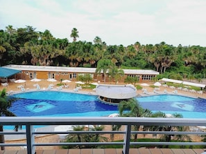 Ein Hotel mit großem Schwimmbad, Liegestühlen und einem überdachten Bereich.