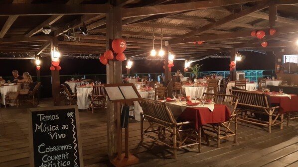 An outdoor dining area with tables set for a meal, a sign indicating live music, and a menu board.