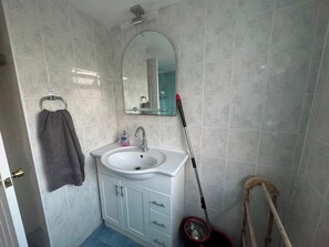 A bathroom with a white sink, a mirror, a towel rack, and a mop. - Apartment Sleeps 6 With Free Wifi, Free Parking (Ashford)