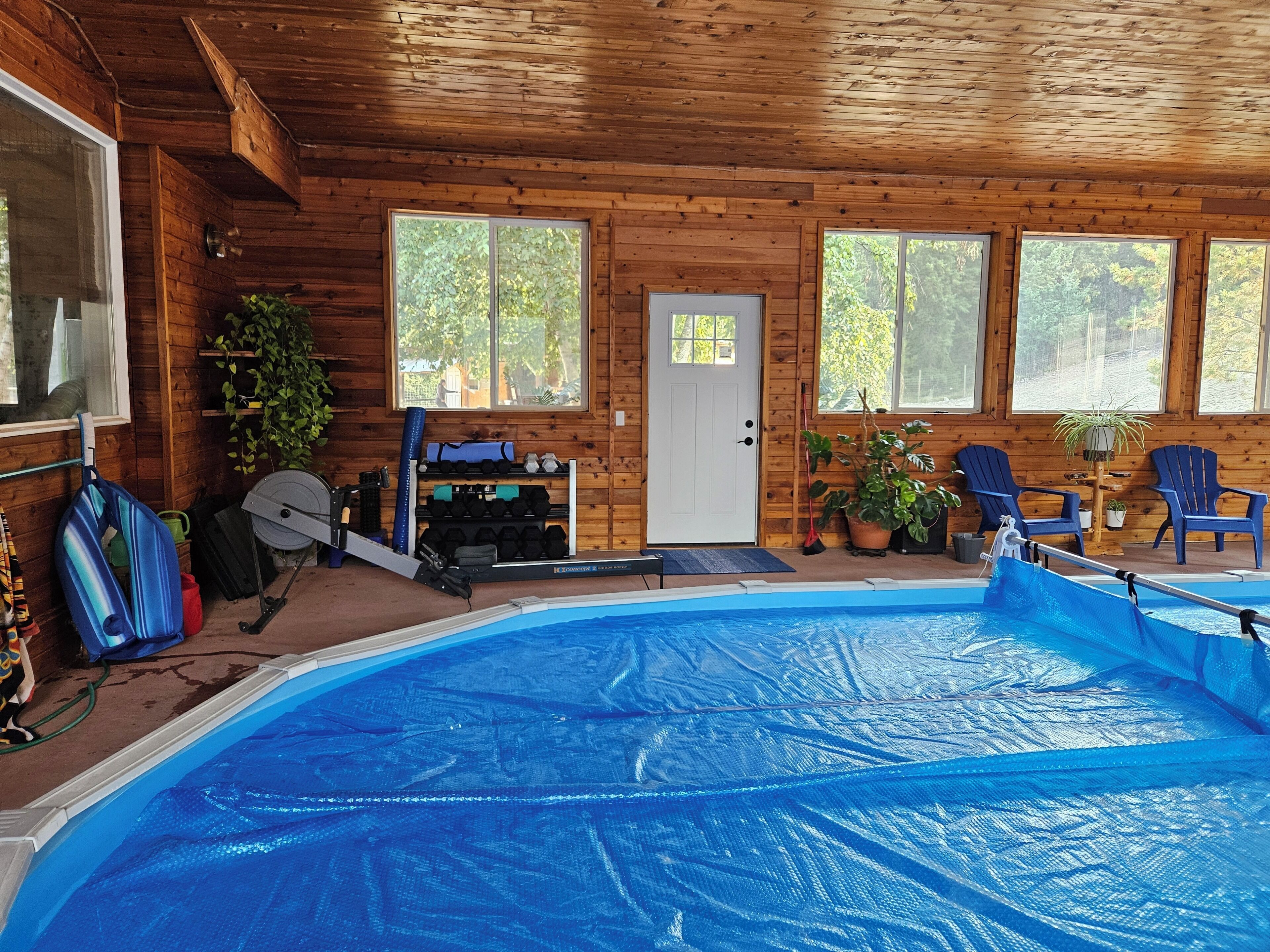 A wooden cabin with a swimming pool, exercise equipment, and seating areas.