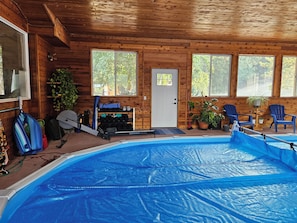 Een houten vakantiehuis met een zwembad, fitnessapparatuur en zitplekken.