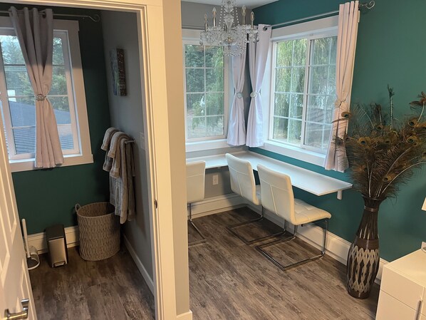 A bathroom with a bathtub, a sink, and a window with curtains. There is a towel rack and a trash can.