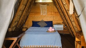Ein gemütlicher, dreieckiger Raum mit einem Bett, Holzmöbeln und einer gewebten Decke.