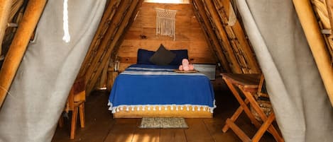 Une pièce chaleureuse, aménagée comme une tente en bois, avec un lit, des oreillers et une décoration en macramé suspendue.