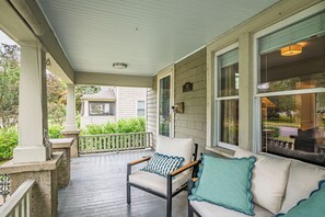 A covered porch with a cushioned seating area, a small table, and a view of a residential street. - NEW! Prelaunch Pricing Close to Track and Downtown (Saratoga Springs)