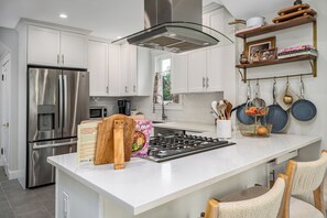 A modern kitchen with white cabinetry, stainless steel appliances, and a central island with a gas stove. - NEW! Prelaunch Pricing Close to Track and Downtown (Saratoga Springs)
