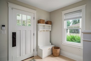 A clean, minimalist entryway with a white door, a small bench, and a basket. - NEW! Prelaunch Pricing Close to Track and Downtown (Saratoga Springs)