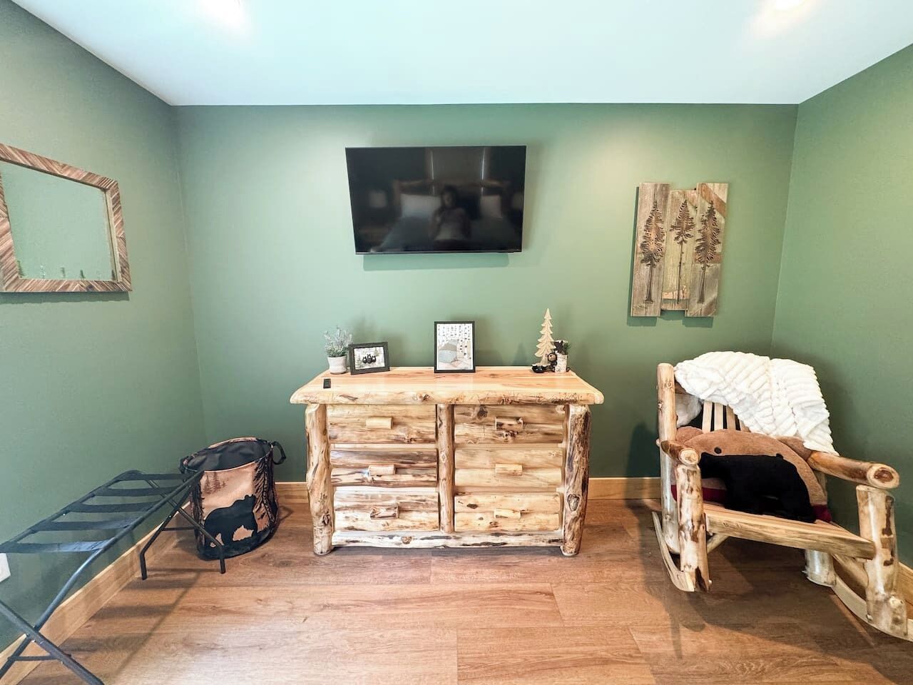 A room with a wooden desk, a chair, a television, and a mirror on the wall.