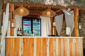 Eine Barbereich mit Holzwandverkleidung, einem Strohdach und einem gekühlten Kühlregal.