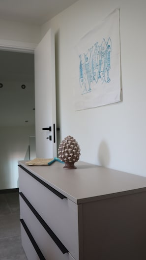 A room with a white dresser, a pine cone decoration, and a wall with a blue fish drawing. - Villa Zagara, a villa with a pool where families and friends can relax (Piane Vecchie)