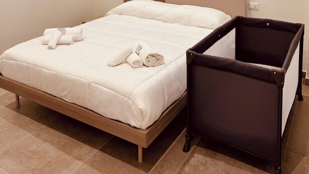 Habitación de hotel con una cama, una mesita y dos lámparas fijadas a la pared.