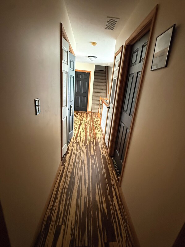 A hallway with patterned flooring, wooden doors, and a staircase leading to an upper level.