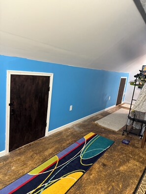 A hallway with blue walls, a dark door, and a colorful rug on a wooden floor.