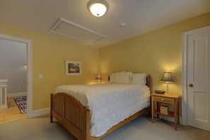 Un dormitorio con una cama de madera, lámparas de noche, una mesita de noche, una puerta y un aplique de techo.