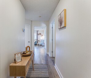 Ein Flur mit einer hölzernen Bank, einem Korb und einem gerahmten Bild links.