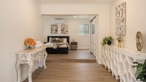 A bedroom with a bed, bedside tables, and a view through an open door. - Sun Chaser | Pool | Spacious Home | Parking (Monterey Park)