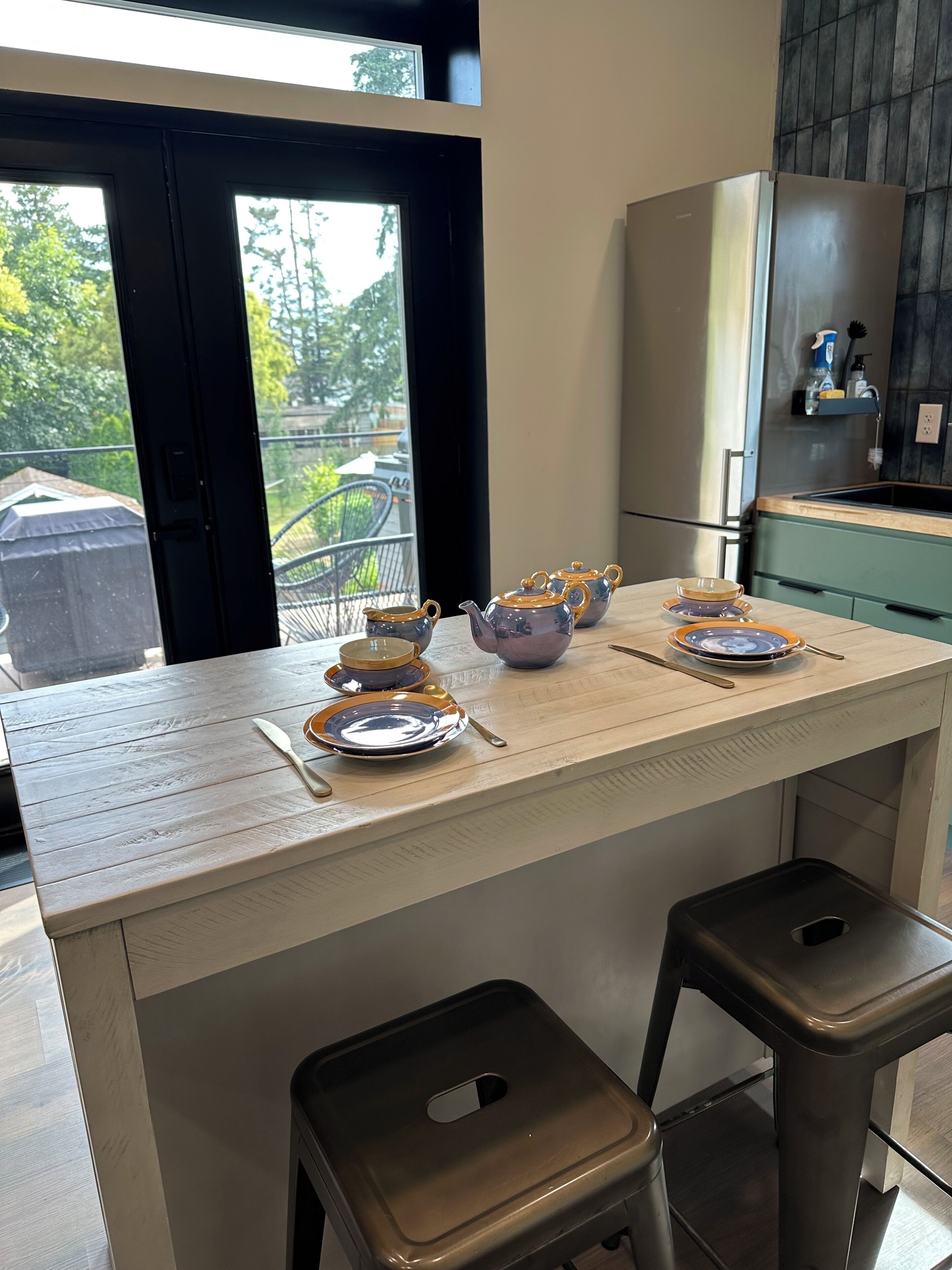 A kitchen with a central island, a refrigerator, and a window with a view of greenery.