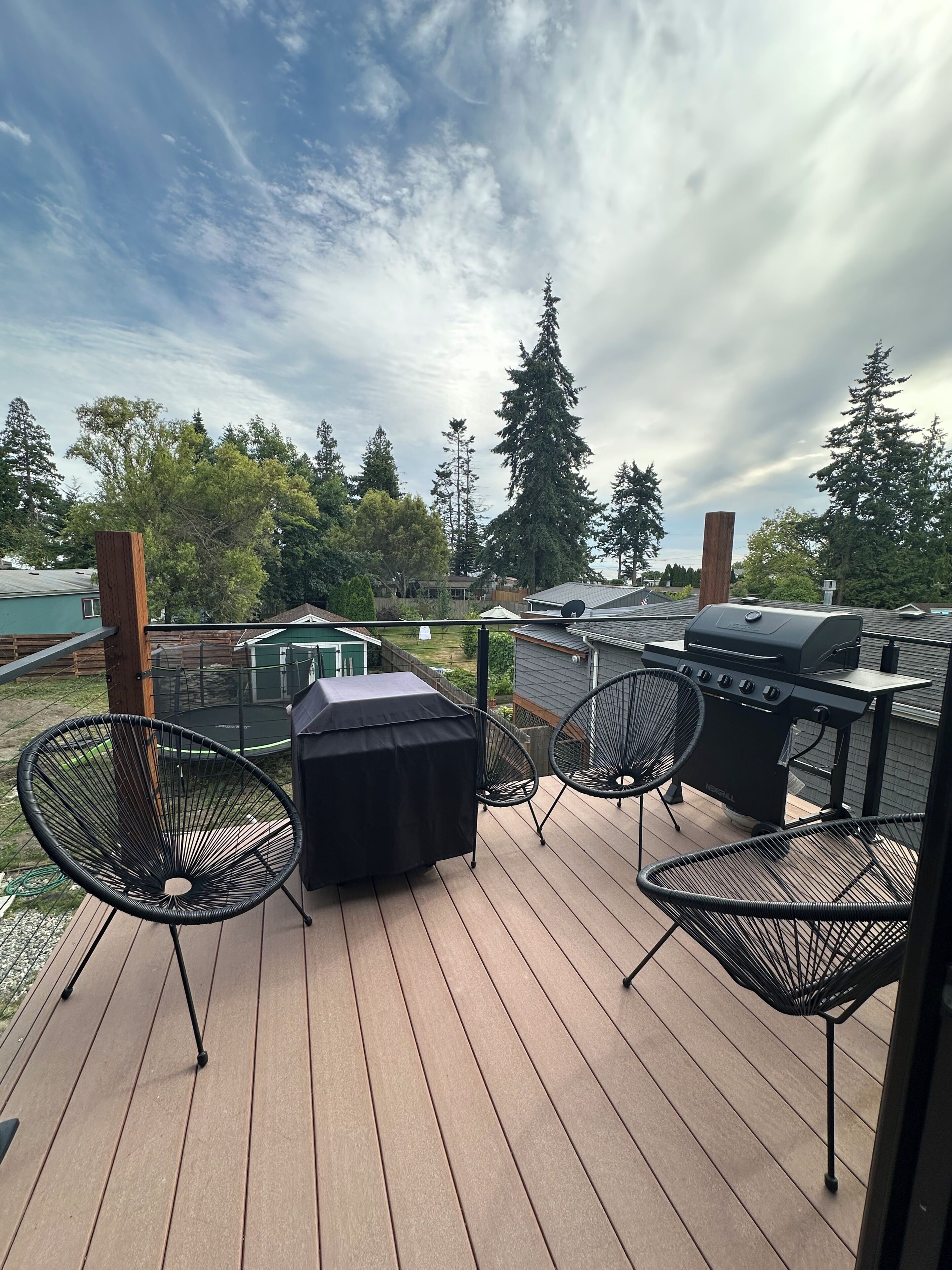 A deck with a grill, chairs, and a covered table.