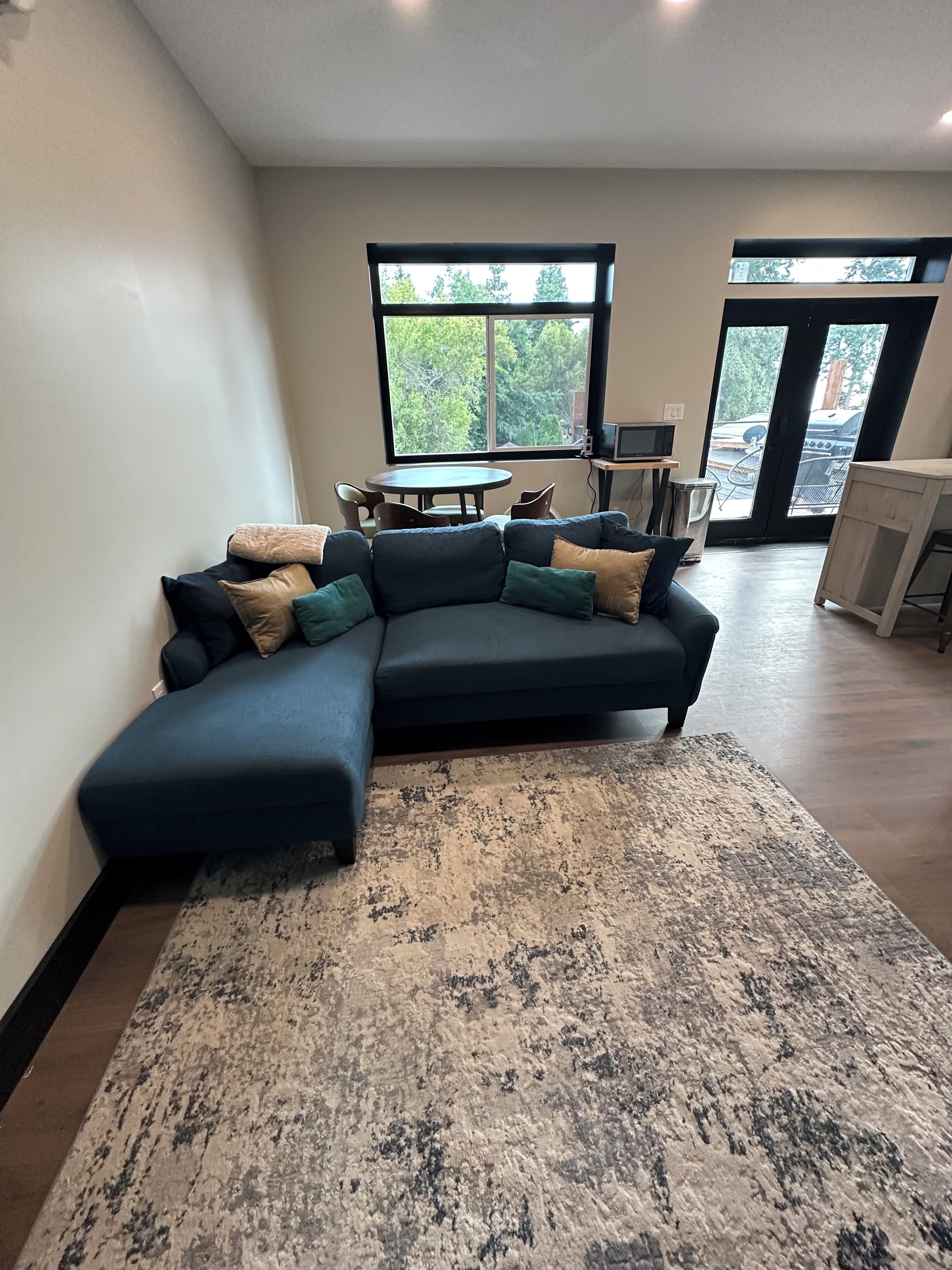 A modern living room with a sectional sofa, a round coffee table, and a large window providing a view of the outdoors.