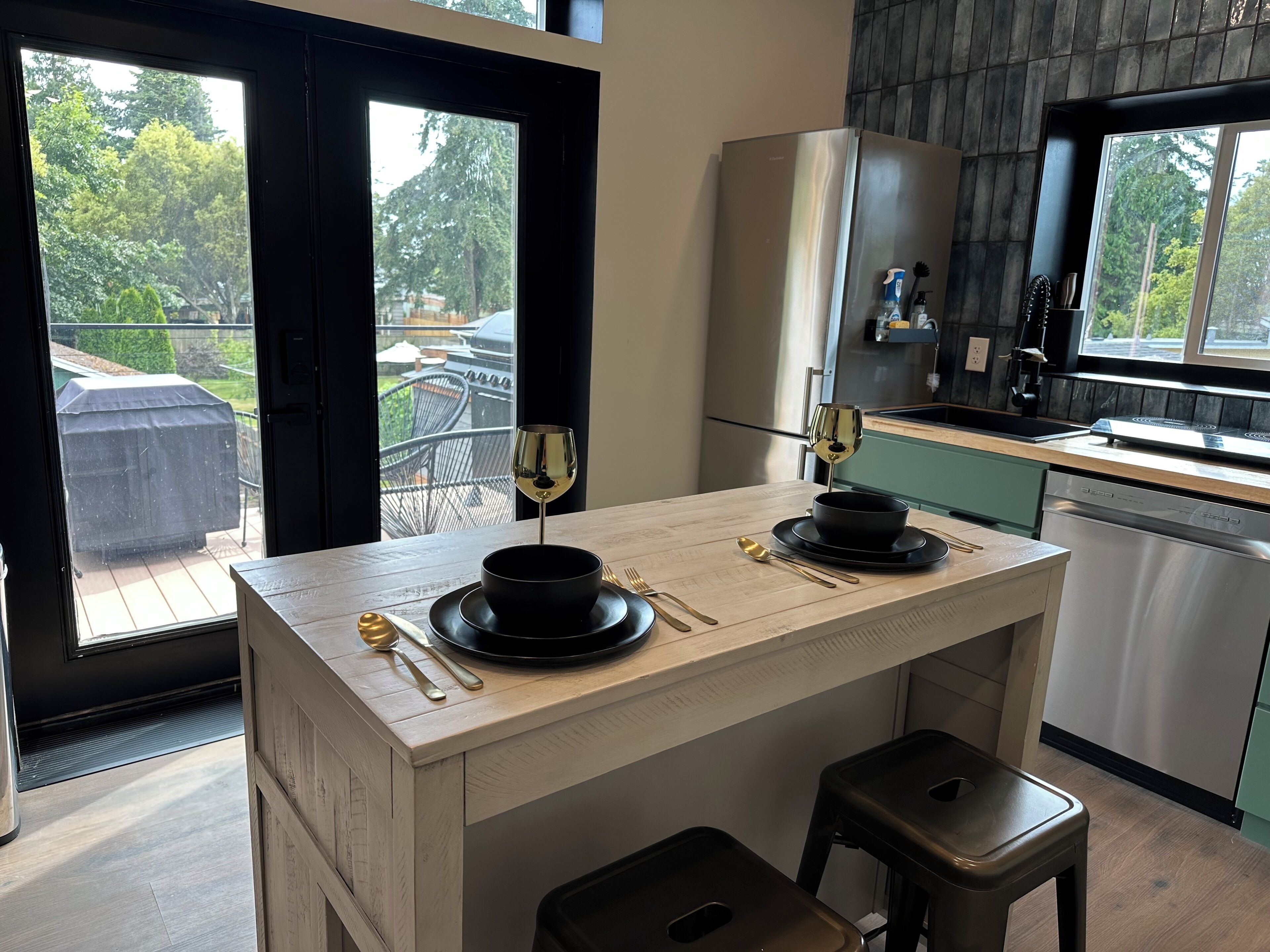 A modern kitchen with a central island, a refrigerator, and a view of the outdoors.