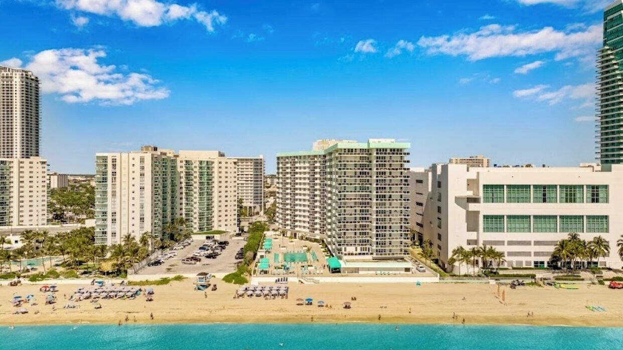 A beachfront hotel with multiple high-rise buildings, a pool area, and beach access.