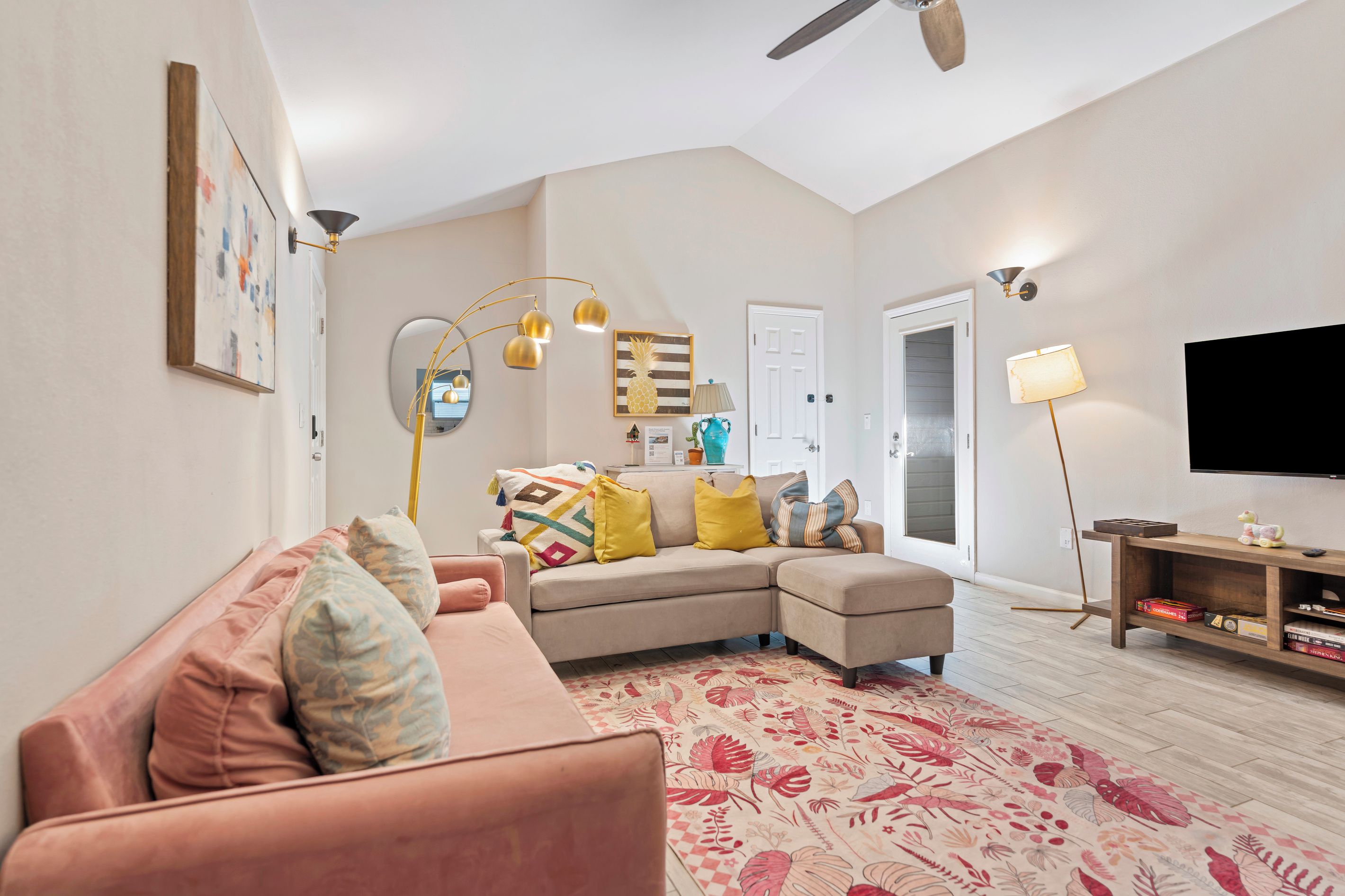 A living room with a sectional sofa, a flat-screen TV, and a ceiling fan.