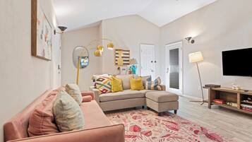 A living room with a sectional sofa, a flat-screen TV, and a ceiling fan.