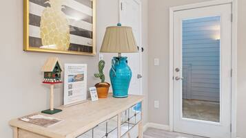 A wooden console table with a lamp, a pineapple artwork, and a cactus decoration.