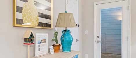 A wooden console table with a lamp, a pineapple artwork, and a cactus decoration.