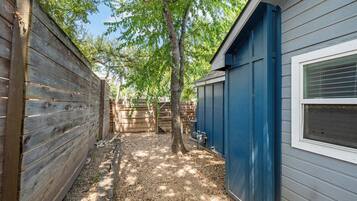 A narrow outdoor pathway flanked by wooden fences and a blue building with a window.