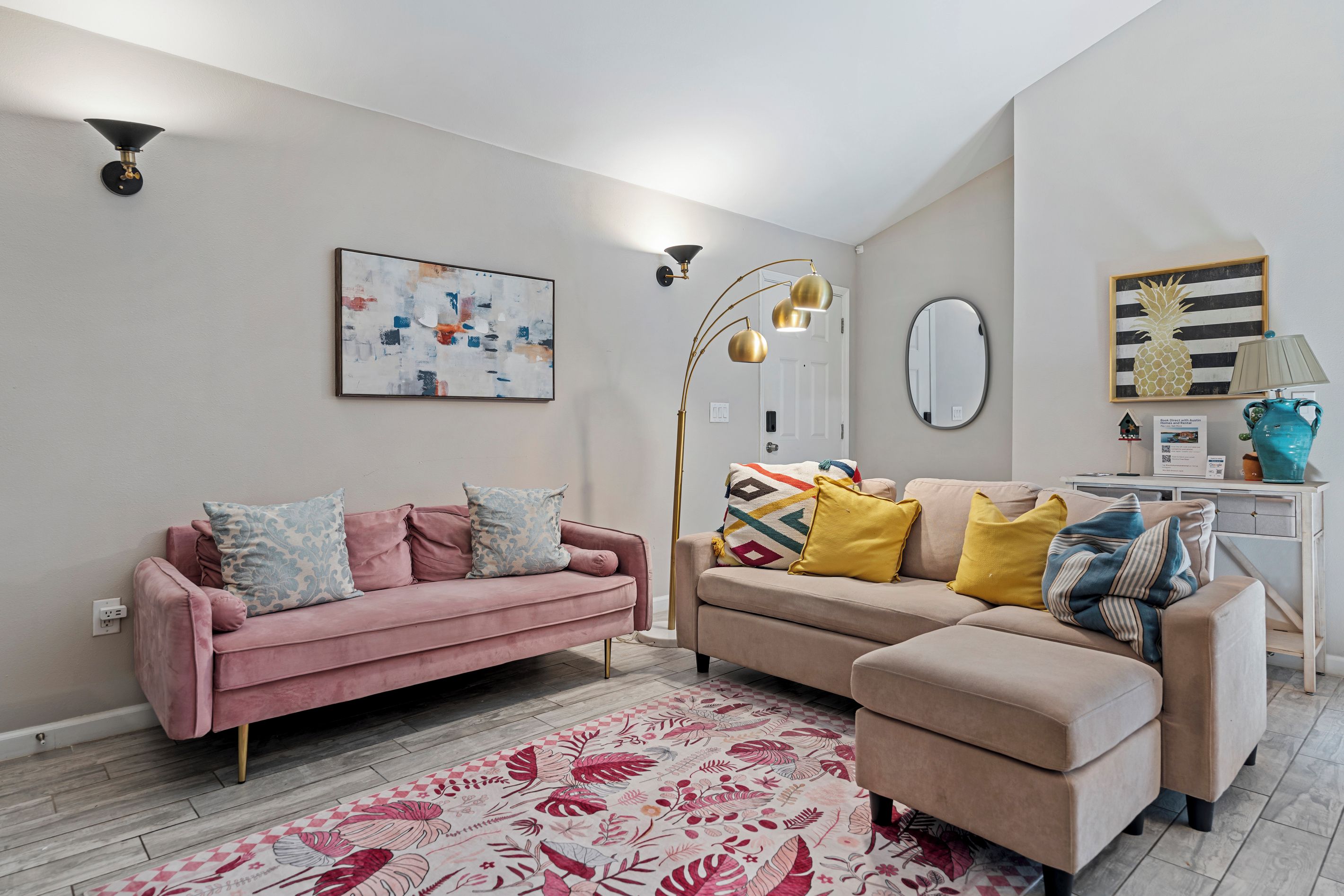 Un salon comprenant deux canapés, une table basse, un lampadaire, un tableau, un miroir et un ananas décoratif.