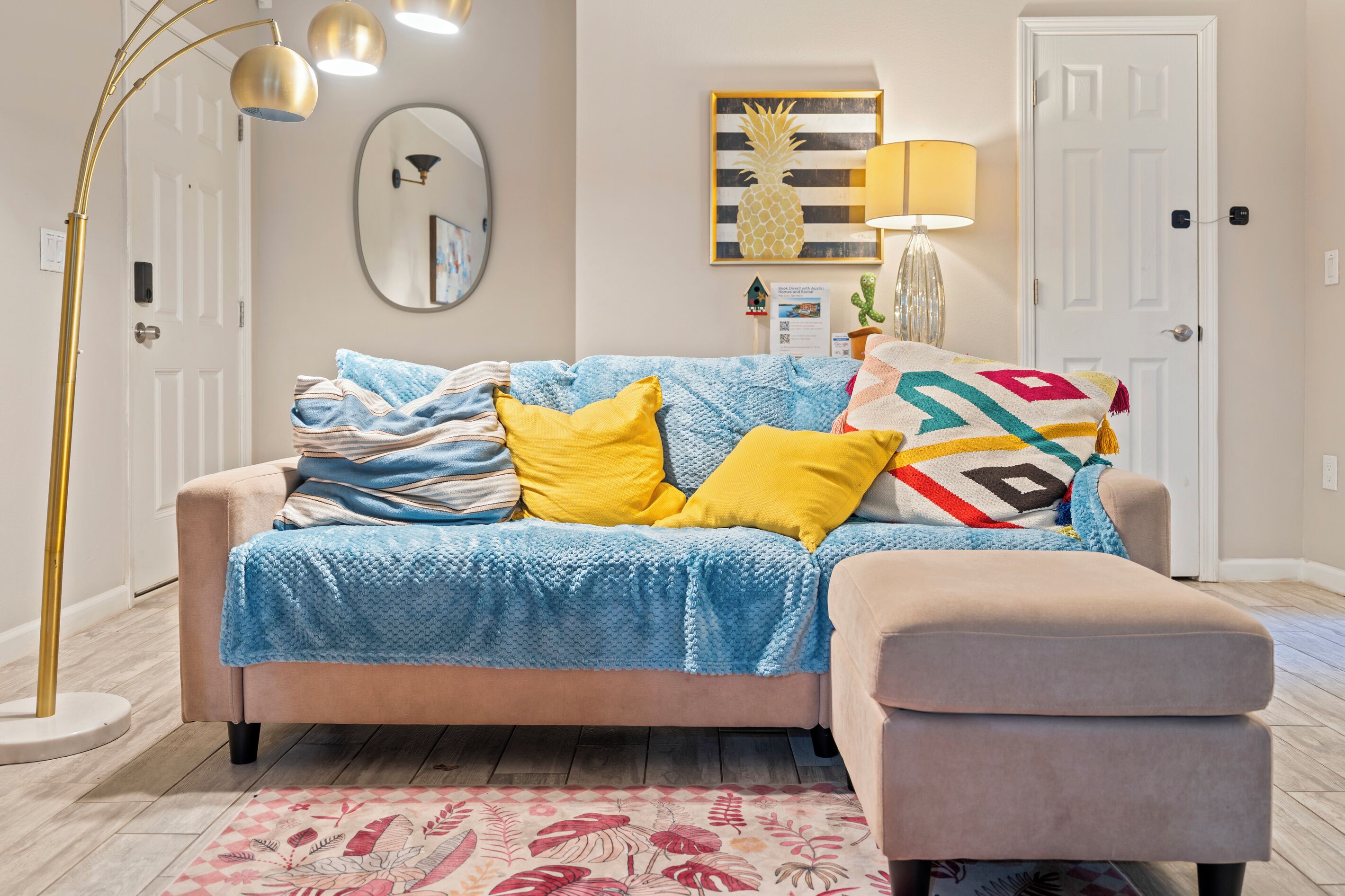 A living room with a sofa, a side table, a lamp, a mirror, and a door.