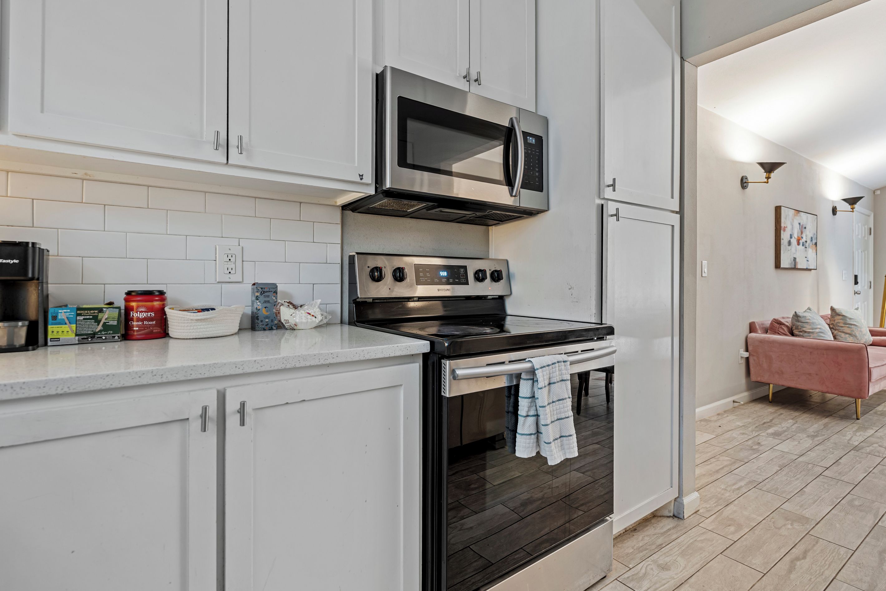 A modern kitchen with white cabinets, a stainless steel stove, and a microwave.