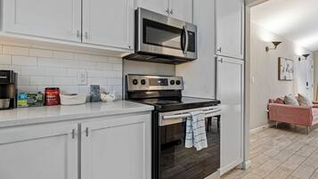 A modern kitchen with white cabinets, a stainless steel stove, and a microwave.