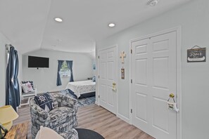 Ein Schlafzimmer mit Bett, Stuhl, Fernseher und einer Tür mit Kreuz-Verzierung.