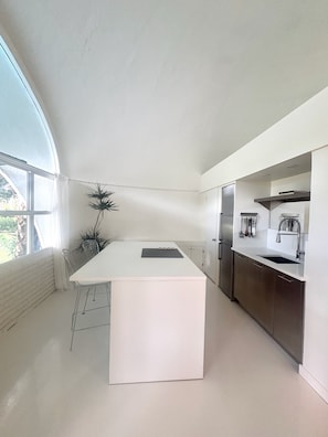 A modern kitchen with a central island, stainless steel appliances, and a large window providing natural light.