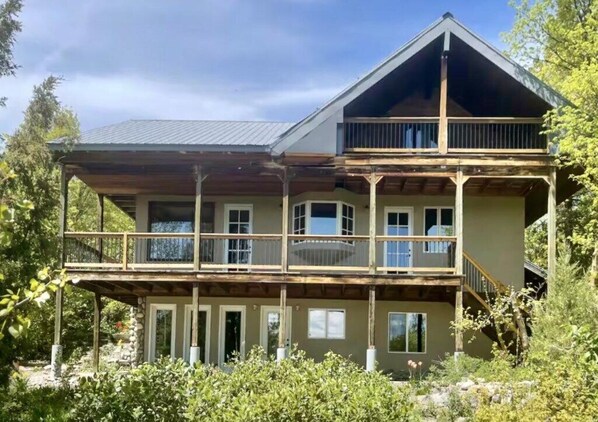 Ein zweistöckiges Holzhaus mit Balkon, umgeben von viel Grün.