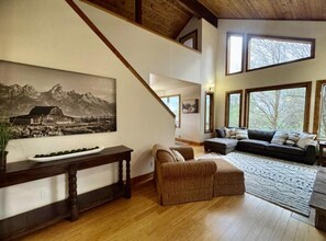 Ein großzügiger Wohnbereich mit einem großen Gemälde, einer hölzernen Bank, einem Sofa und einem Teppich.