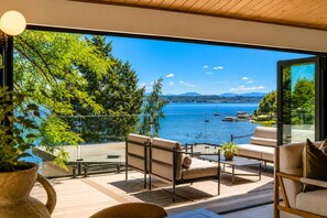 Ein moderner Sitzbereich im Freien mit Blick auf einen See und Berge.