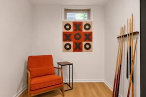 Ein Zimmer mit Billardtisch, einem Sessel und einem an der Wand befestigten Billardstöcken-Ständer.