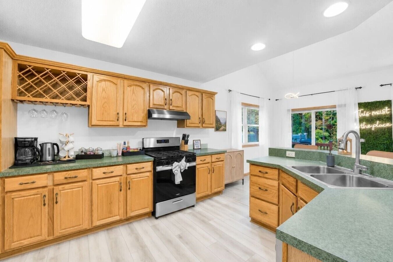 Una cocina moderna con armarios de madera, una campana extractora de acero inoxidable y un ventanal con vistas a zonas verdes.