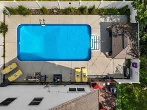 Eine Vogelperspektive auf ein Wohnhaus mit Swimmingpool, zwei Liegestühlen und einer überdachten Terrasse.