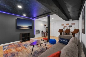 Ein modernes Wohnzimmer mit Sternenhimmel, einer Couch, einem Couchtisch und einem Essbereich mit Stühlen.