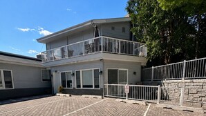 Ein zweistöckiges Gebäude mit einem kiengepflasterten Innenhof, einem Balkon mit Geländer und einer Steinmauer.