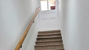 A staircase with a wooden handrail leading to a door with a window above it. - The Cottage - ANDERT AND CONDON (ANDERT ET CONDON)