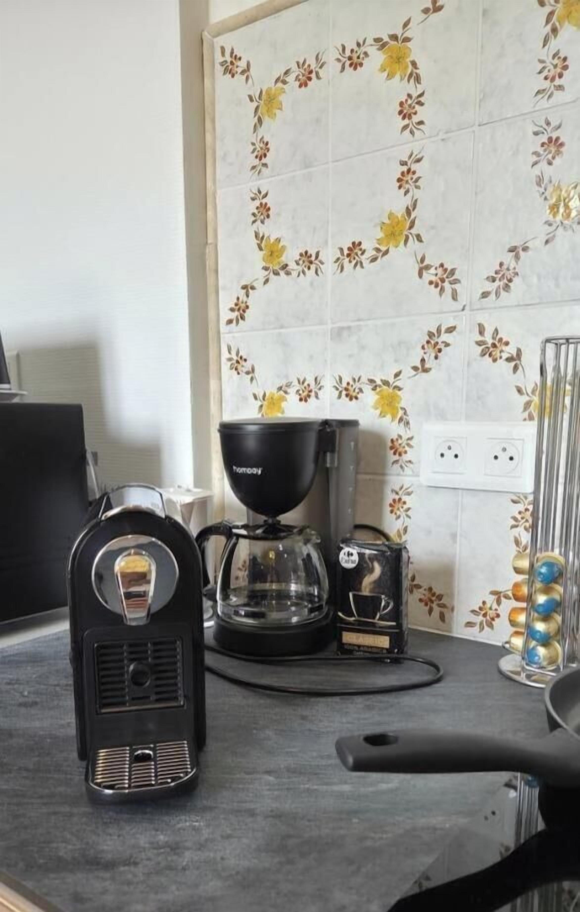 A kitchen with a coffee maker, a scale, and a kettle on the counter.
