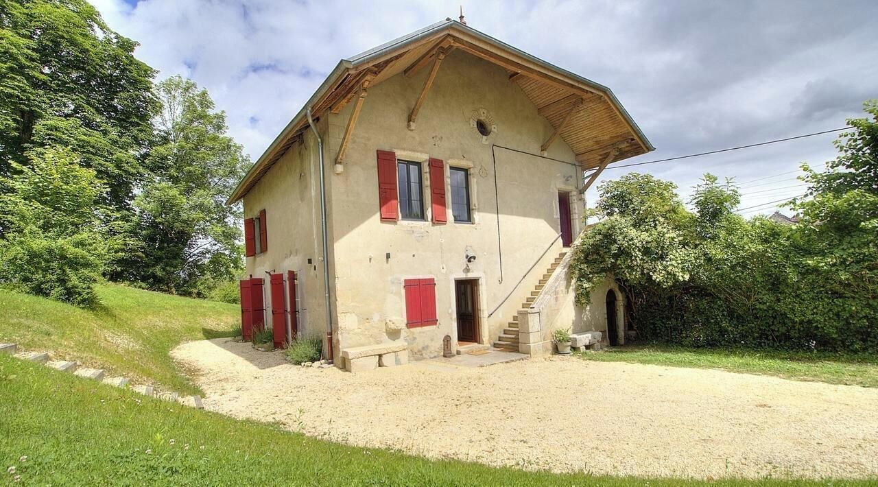 Un bâtiment à deux étages, doté d’un toit en pente, d’un escalier menant à l’entrée et d’une allée gravillonnée.