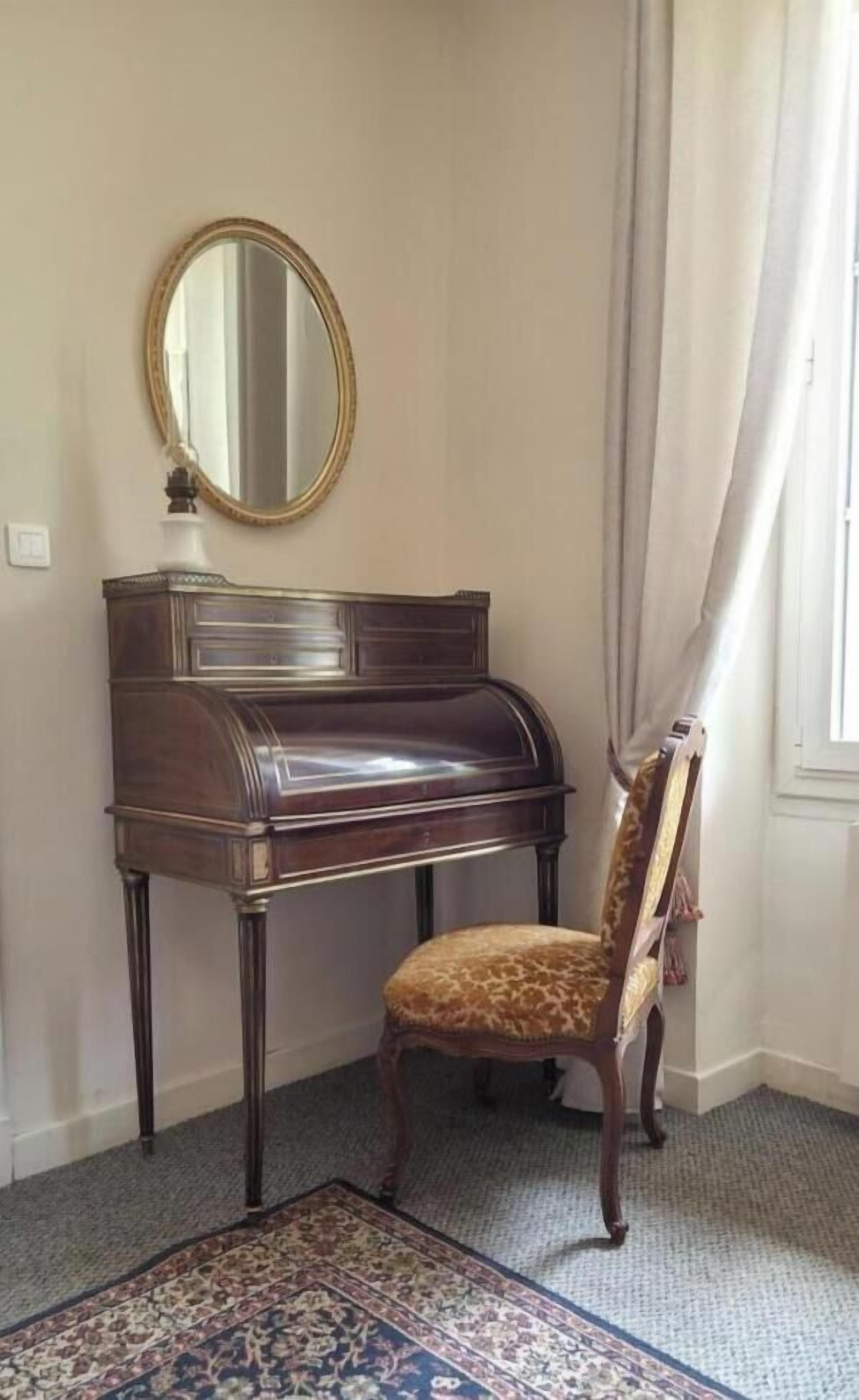 A piano with a mirror above it, a patterned rug, and a chair with a leopard print cushion.