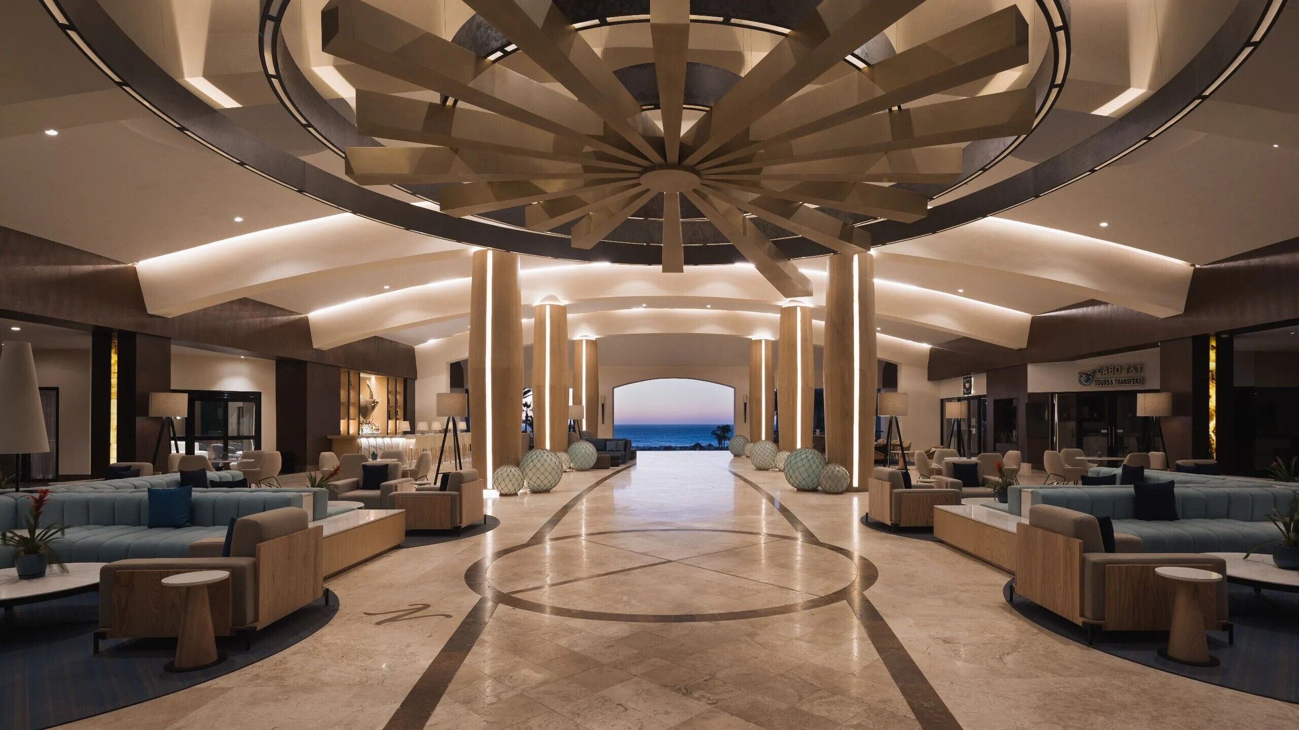 A spacious lobby with a central open area, seating arrangements, and a view towards the sea.