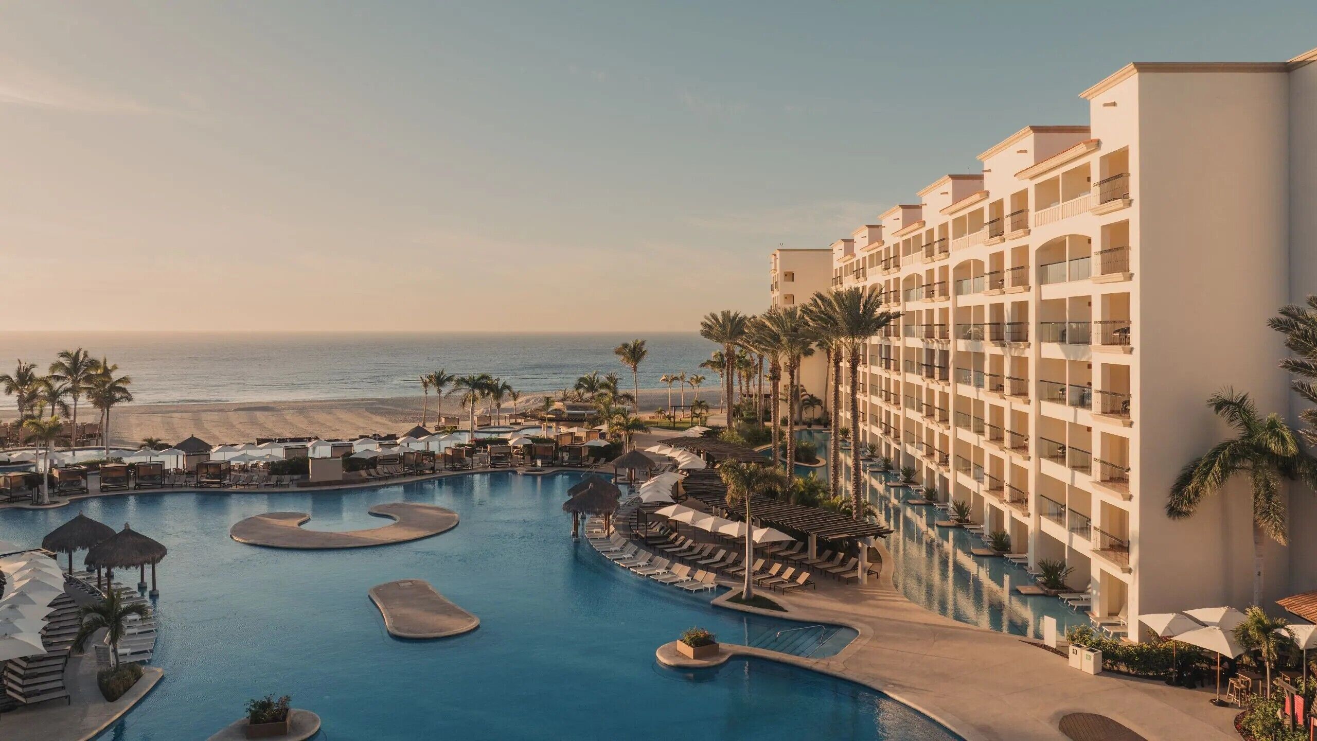 A resort with a large pool area, multiple swimming pools, and a beach view.
